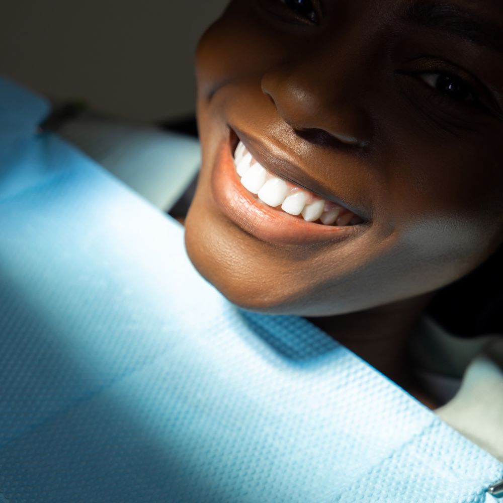 Black lady patient with a beautiful new smile after composite bonding by Dr. Theodora Bravis at Thames Dental & Skin, Thames Ditton, Surrey