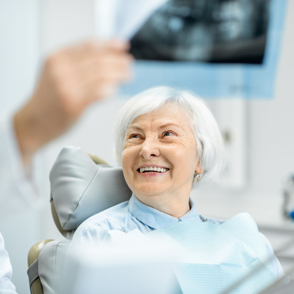 Elderly woman smiling with her new dentures by Dr. Theodora Bravis at Thames Dental & Skin in Thames Ditton, Surrey